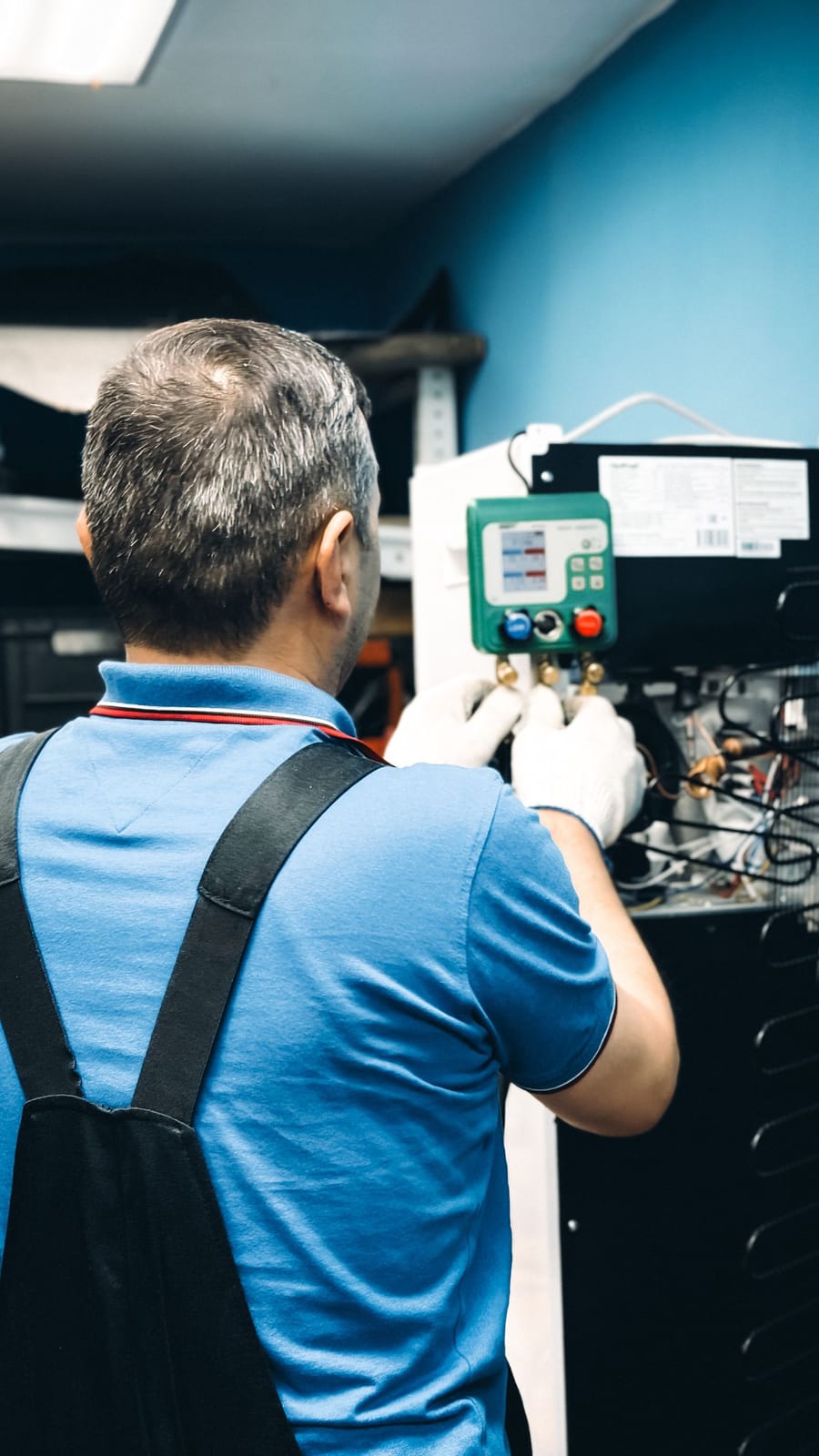 Technician in a blue polo servicing appliance coils
