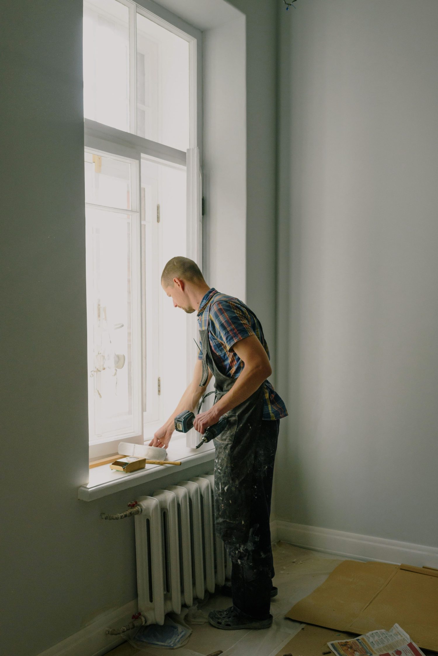 Worker prepping a window sill in an empty rental unit