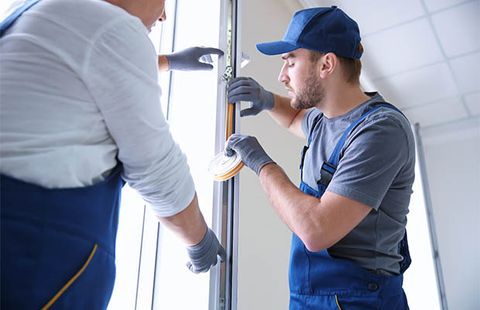 Two technicians reviewing work at a door frame