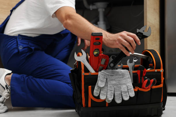 Technician kneeling beside an open tool bag of wrenches and levels