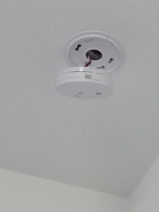 New smoke detector being mounted to a ceiling plate