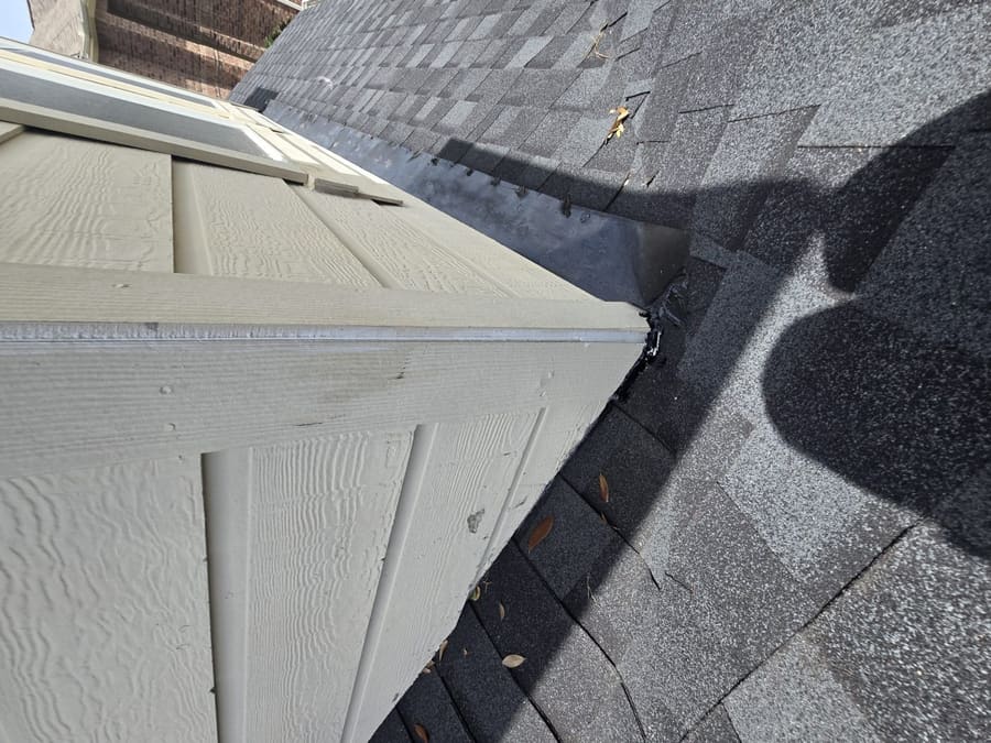 New flashing sealed along a roofline where siding meets shingles